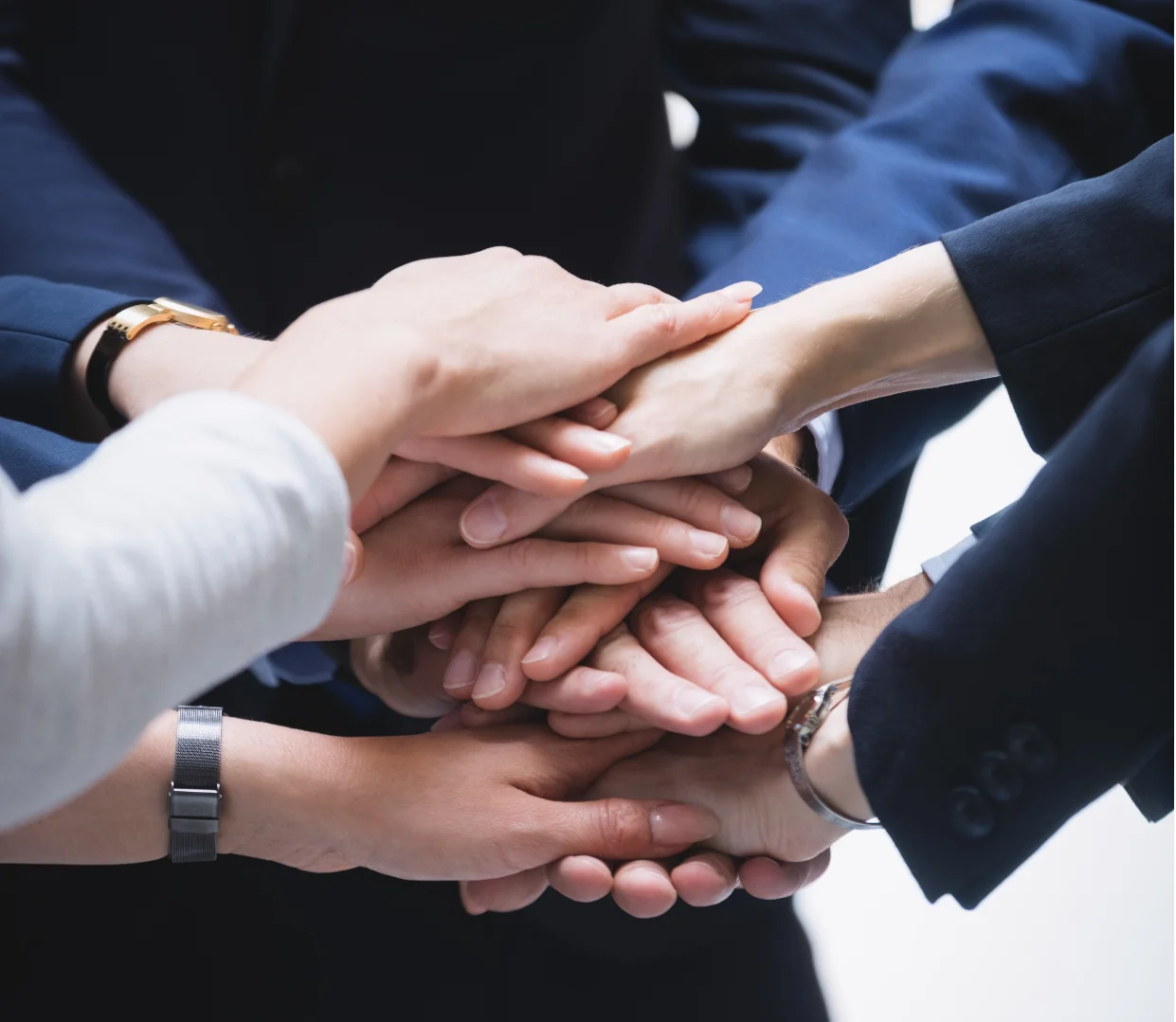 A group of professionals placing their hands together in a show of unity and teamwork, symbolizing the importance of transparency and effective communication in SEO outsourcing services provided by Zero Dimensions.