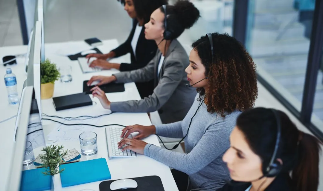 Four female customer support agents working at computers in an office, representing a successful local SEO campaign that increased online inquiries by 70% for a Chicago real estate agent through targeted keywords and improved user experience.