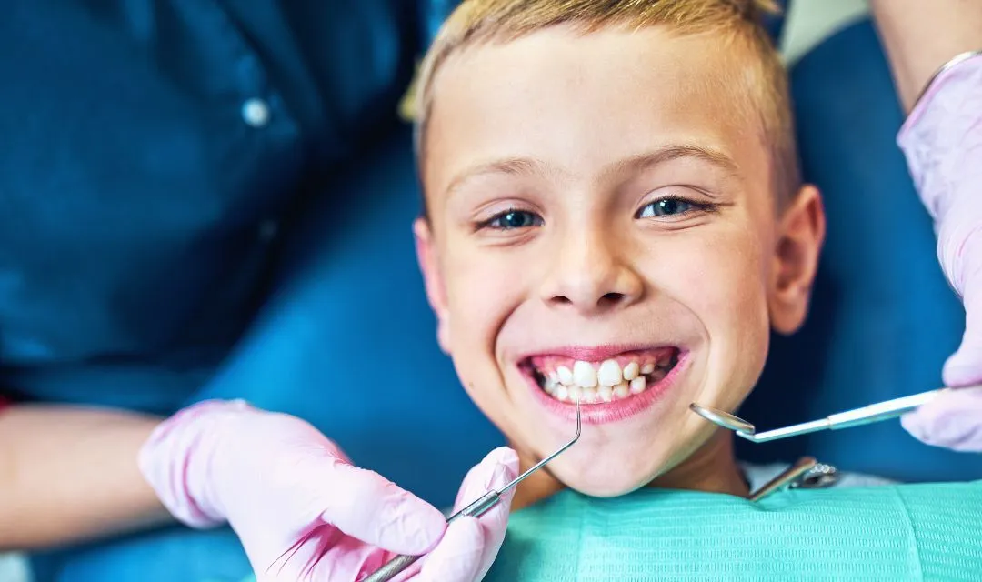 Smiling young boy at a dental appointment, symbolizing the success of SEO strategies to increase the patient base for a pediatric dentist by improving local search visibility and online presence.