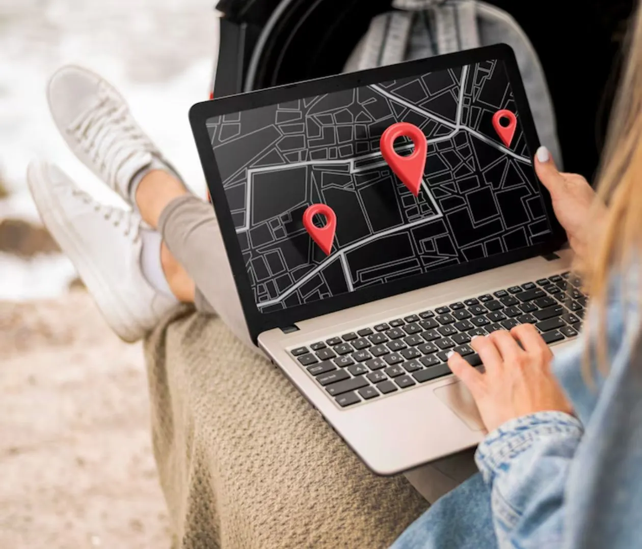 Person using a laptop displaying a digital map with red location pins, representing the use of location-based keywords in SEO strategies for dentists to attract local patients.