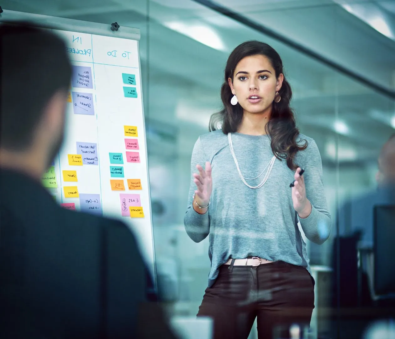 Professional woman presenting an SEO strategy on a whiteboard with colorful sticky notes, emphasizing a results-oriented approach to law firm SEO with measurable outcomes and continuous improvement.