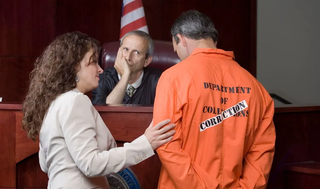 Criminal defense lawyer consulting with a client in an orange jumpsuit in a courtroom, highlighting a criminal defense law firm's successful SEO strategy to improve local search visibility and attract more client inquiries through targeted keywords and optimized landing pages.