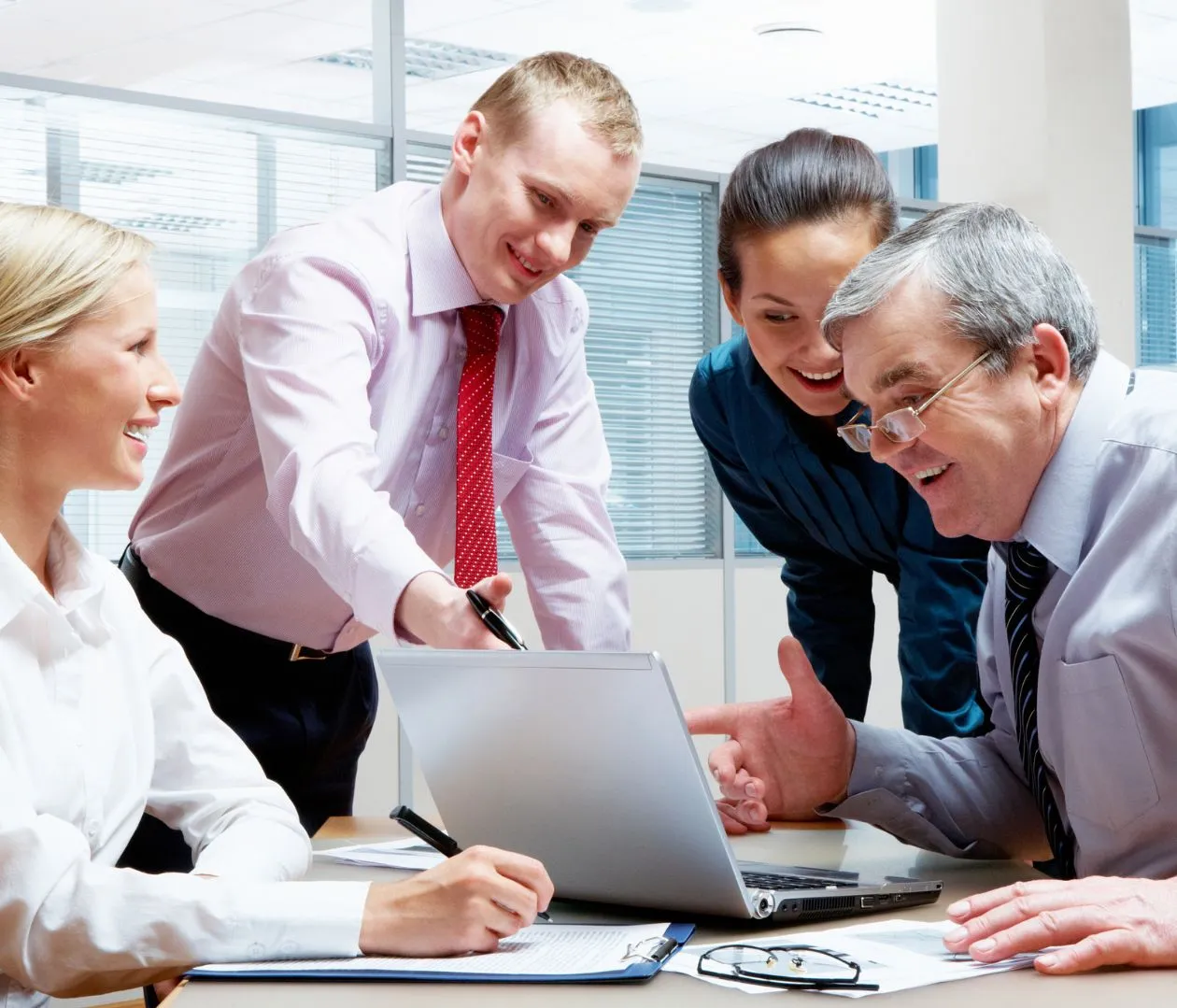 A group of business professionals discussing strategy around a laptop, representing how effective NetSuite SEO can drive relevant traffic and increase conversion rates through optimized online engagement.