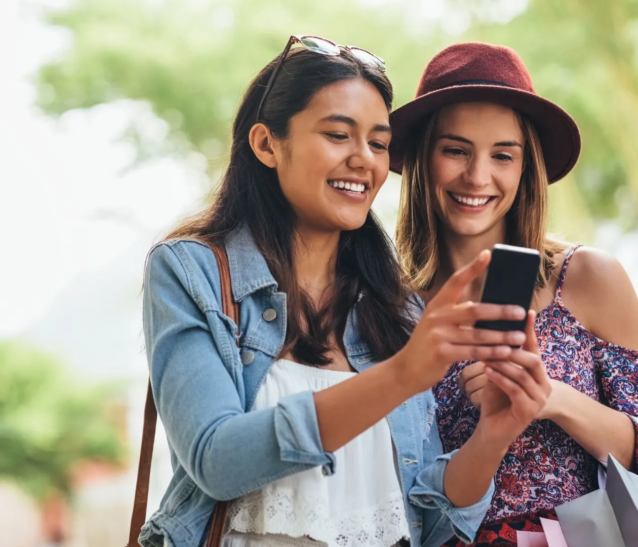 Two smiling women looking at a smartphone, symbolizing improved user experience through optimized NetSuite SEO practices like faster loading times, better mobile responsiveness, and intuitive navigation.