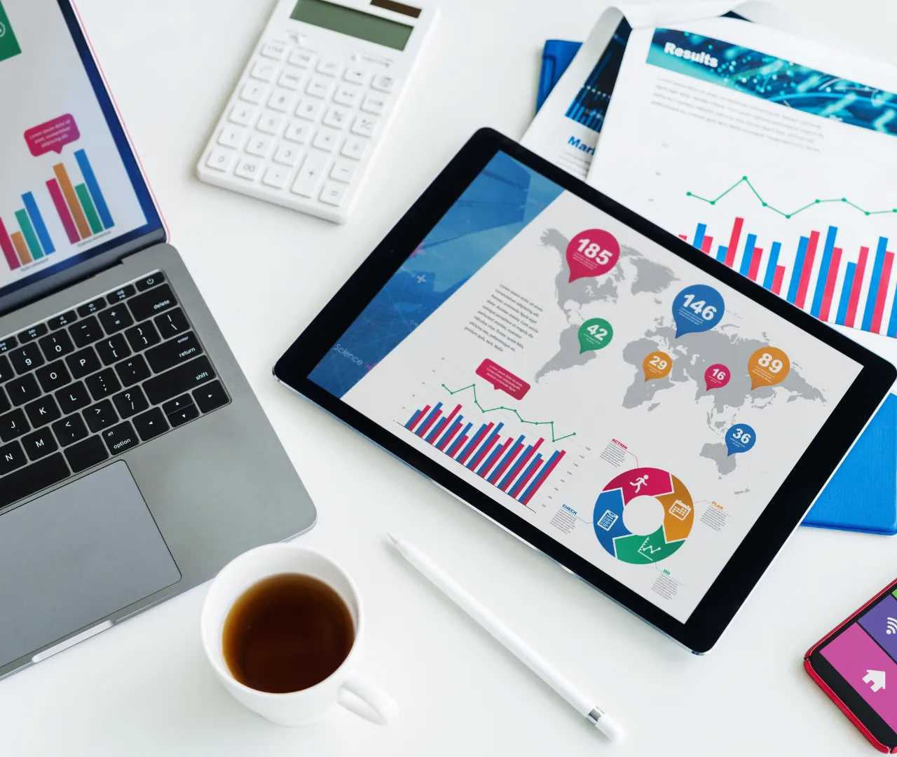 Tablet displaying global data and charts, surrounded by a laptop, calculator, and documents, symbolizing the thorough keyword research and strategic planning involved in a professional NetSuite SEO agency's approach.